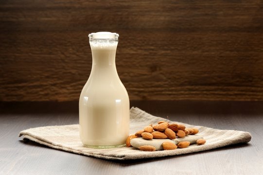 Almond milk in bottle with raw almonds