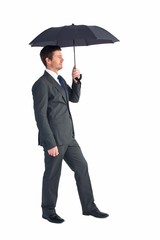 Businessman sheltering under black umbrella