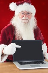 Naklejka premium Composite image of happy santa showing laptop screen