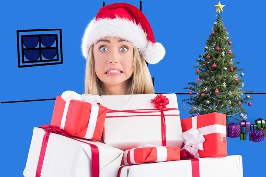 Composite image of festive blonde holding pile of gifts