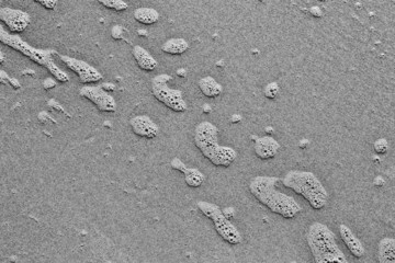 Fototapeta na wymiar Water foam on the sand background, black and white