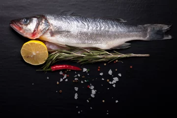 Poster Fresh sea fish lying on dark background with spices. Space for t © strannik_fox