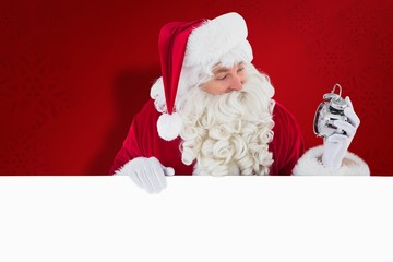 Composite image of happy santa holding alarm clock and sign
