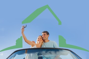 Cheerful couple standing in red cabriolet takking picture