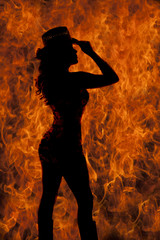 cowgirl standing in fire silhouette holding hat