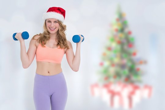Composite image of festive fit blonde holding dumbbells