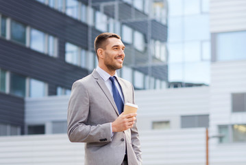 young serious businessman with paper cup outdoors