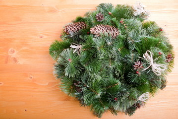 Christmas wreath of pine needles with cones on a yellow board