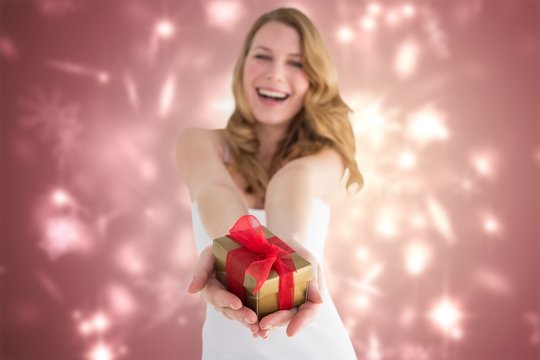 Composite image of smiling blonde offering a gift