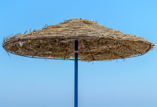 Straw umbrella on blue sky background