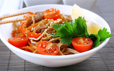 Chinese noodles with vegetables and roasted meat in bowl