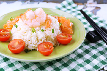 Boiled rice and shrimps, salmon on plate, on wooden background