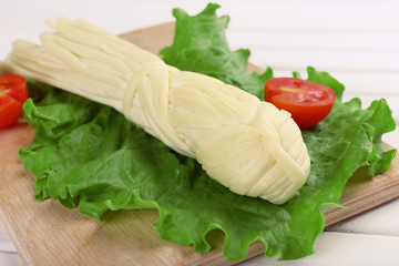 Smoked braided cheese on wooden table
