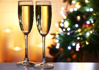Champagne glasses on table, on fir-tree and fireplace
