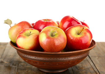 Bowl of red apples on wooden table, on white background