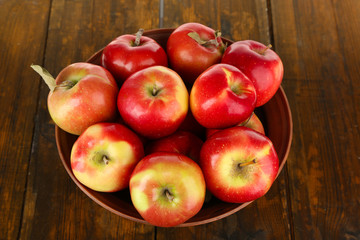 Bowl of red apples on wooden table background