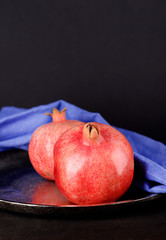 Juicy ripe pomegranates on wooden table, on dark background