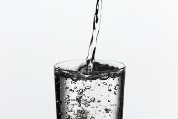 Pouring water from bottle on  glass isolated on white