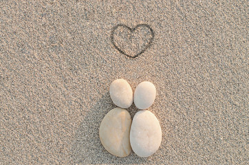 Pebbles shapes lovers with heart on the sand