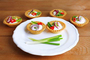 Tartlets with greens and vegetables with sauce on plate on