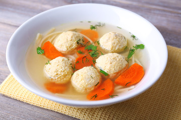Soup with meatballs and noodles in bowl on wooden background