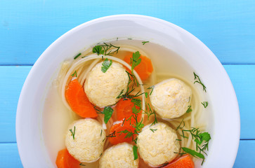 Soup with meatballs and noodles in bowl on wooden background