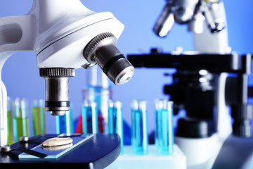Microscopes and test tubes on table, on color background