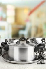 Stainless steel kitchenware on table, on light background