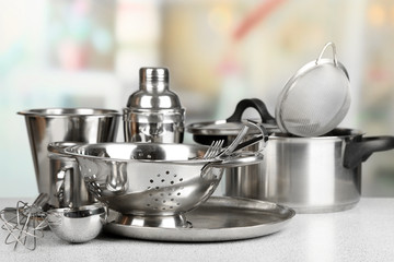 Stainless steel kitchenware on table, on light background