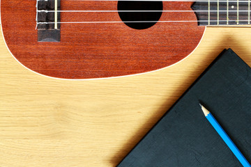 ukulele guitar with  notebook and pencil