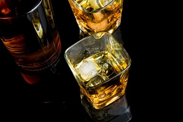 top of view of whiskey with ice in glass on black background