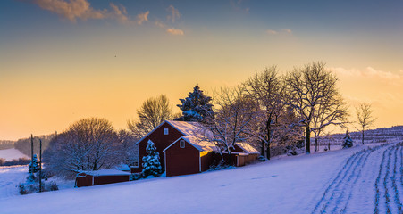 Winter view of a barn on a snow covered farm field at sunset, in © jonbilous