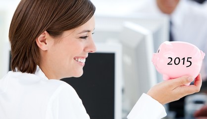 Composite image of smiling businesswoman holding a piggybank