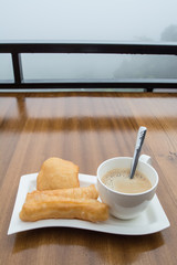 deep-fried doughstick and coffee on wood table,Thai breakfast