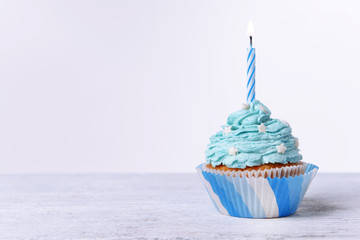 Delicious birthday cupcake on table on white background