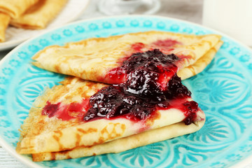 Plate of delicious pancakes with berry jam on wooden background