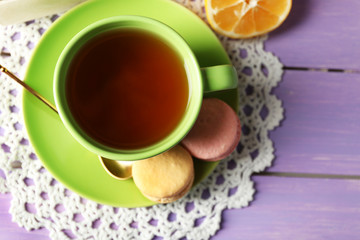Colorful macaroons with cup of tea on wooden background
