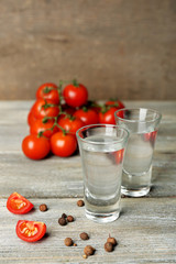 Glasses of ouzo and tomatoes on wooden table