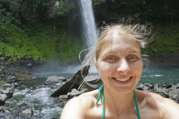 Selfy of a young woman in front of a waterfall