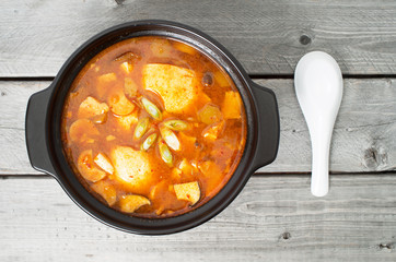 Korean traditional Kimchi soup in a clay pot against wood backgr