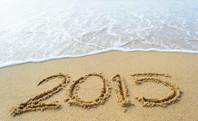 Year ,2015 hand written on the white sand in front of the sea