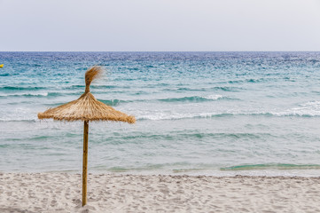 Straw umbrella on sand beach.