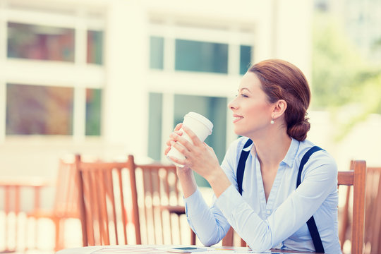 Happy smiling woman drinking coffee in sun sitting outdoor