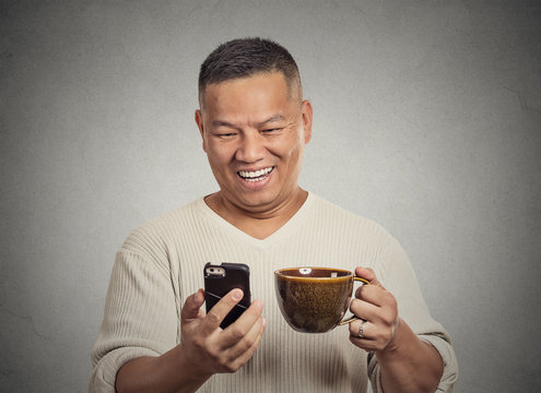 middle aged man reading good news on smartphone drinking coffee