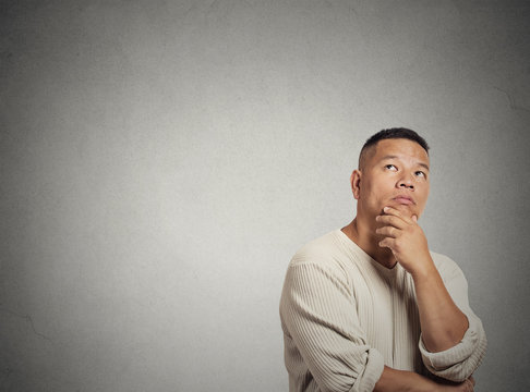 middle aged man thinking looking up on grey wall background 