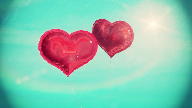 Heart balloons floating against blue sky