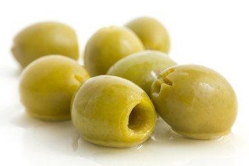 Pitted green olives with brine on white.