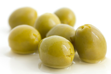 Pitted green olives with brine on white.