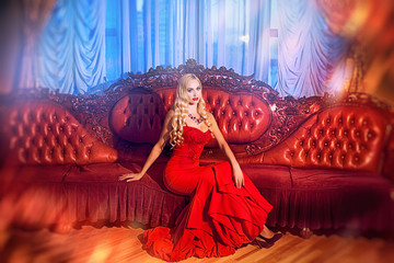 sensual elegant young woman in red dress on recamier indoor shot