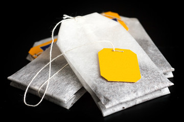 Tagged teabags with string on black surface.